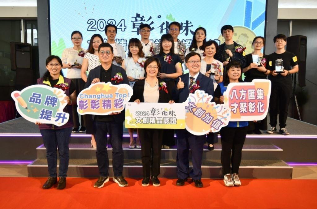 2024彰化味文創精品認證授證典禮大合照，縣府團隊與業者手持活動手牌及獎座於舞台前合影。